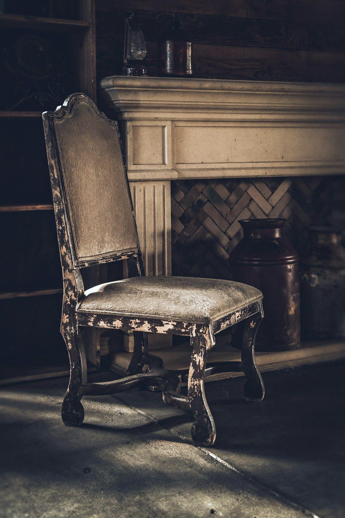 An antique carved chair with a worn upholstered seat, waiting to be recovered